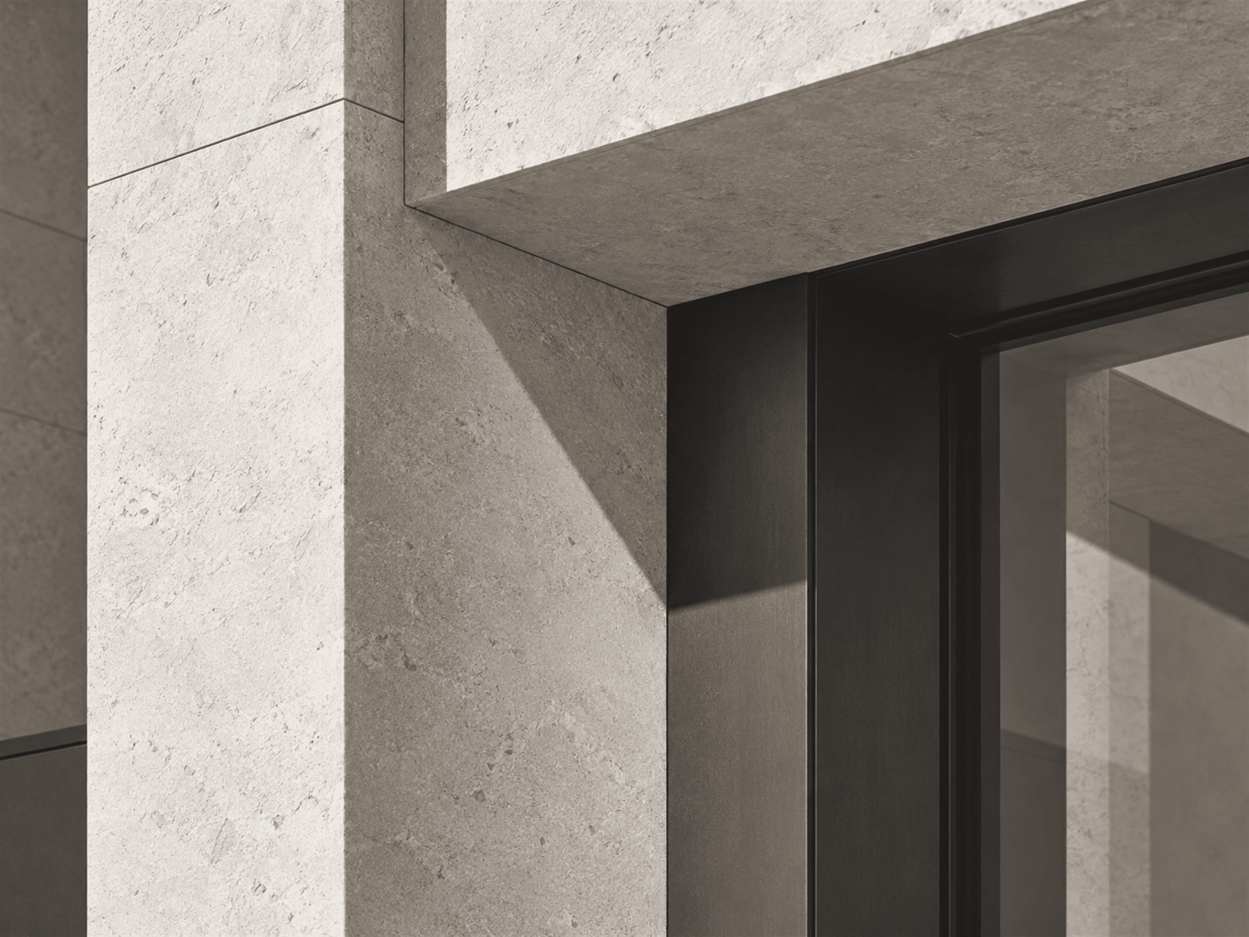 Stone-clad façade detail: a deep window reveal with a dark metal frame, sunlight cutting a diagonal shadow across the stone.